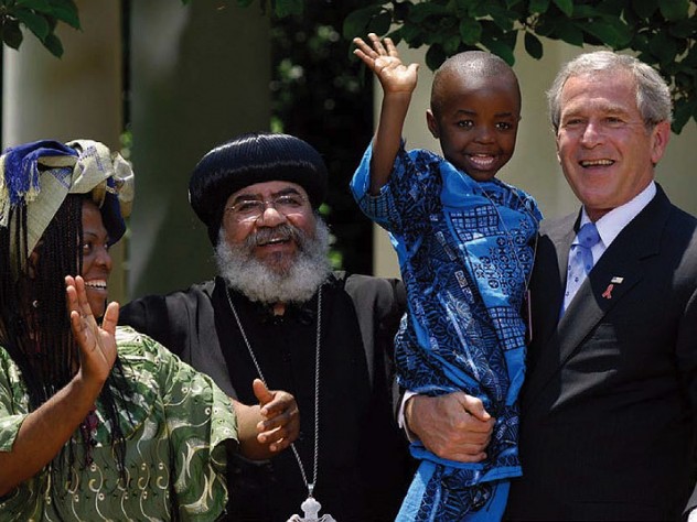 George W. Bush, speaking about PEPFAR (the global AIDS initiative) and holding Baron Mosima Loyiso Tantoh, with Kunene Tantoh, the boy’s mother, then suffering from AIDS, and Bishop Paul Yowakim, May 30, 2007, the White House