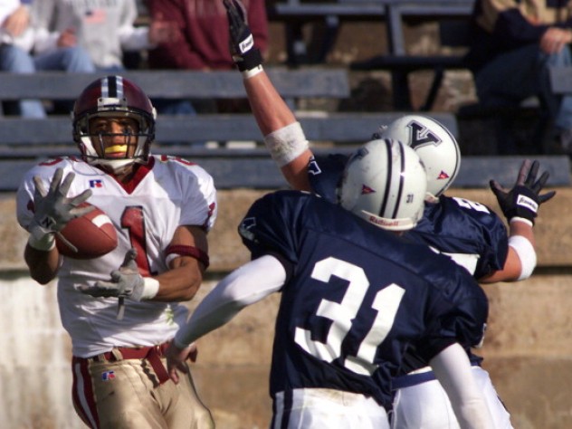 A Harvard receiver catches the ball with two Yale defenders in front