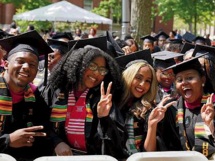 group of Harvard graduates in cap and gown celebrate