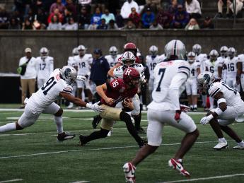 Harvard football player runs with ball as Howard players try to stop him