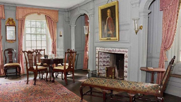 A grand reception room in the main house with an oil portrait hanging above the elegant fireplace.